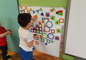 dzieci układają kompazycje z klocków magnetycznych na tablicy